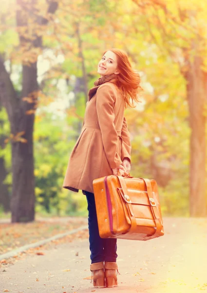 Pelirroja con maleta en otoño al aire libre — Foto de Stock