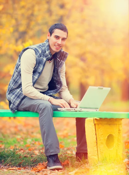 Programmatore con taccuino seduto nel parco autunnale — Foto Stock