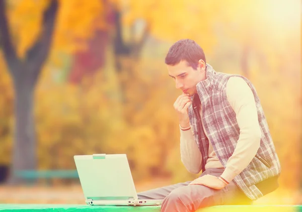 Programmeur avec ordinateur portable assis dans le parc d'automne — Photo