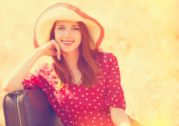 Redhead girl with suitcase sitting at grass — Stock Photo, Image