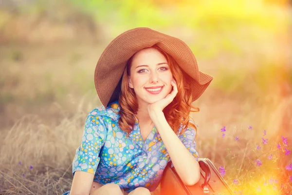 Fille rousse avec valise assise à l'herbe d'automne — Photo