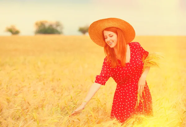 Pelirroja vestida de rojo en el campo de trigo — Foto de Stock