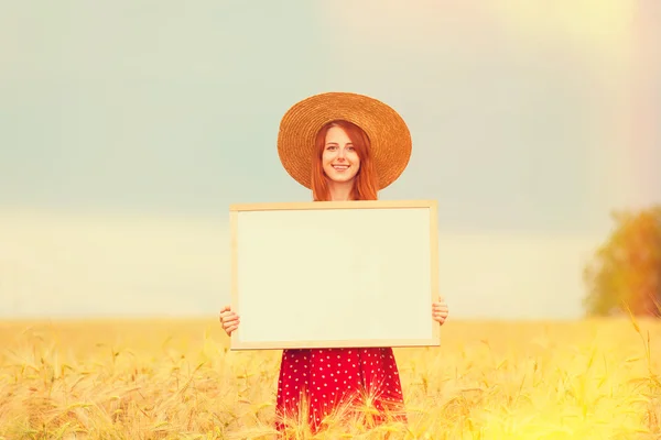 Rödhårig tjej med svart tavla på vete fält — Stockfoto