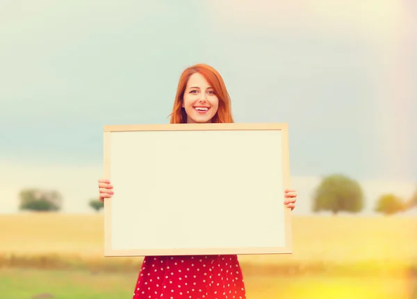 Roodharige meisje met schoolbord aan het tarweveld — Stockfoto