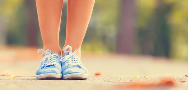 Teenager's foots in gumshoes in the park. — Stock Photo, Image