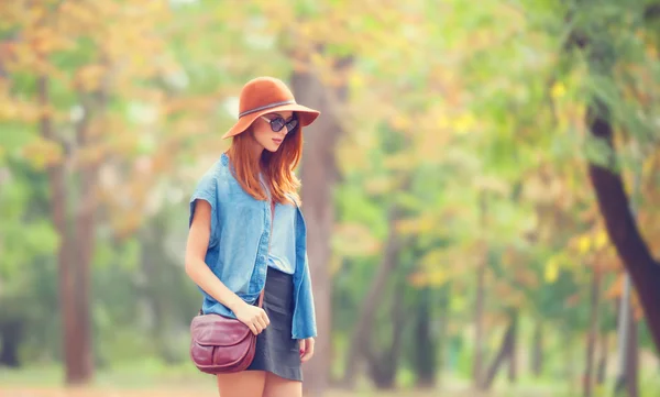 Pelirroja en gafas de sol y sombrero en el parque de otoño . — Foto de Stock