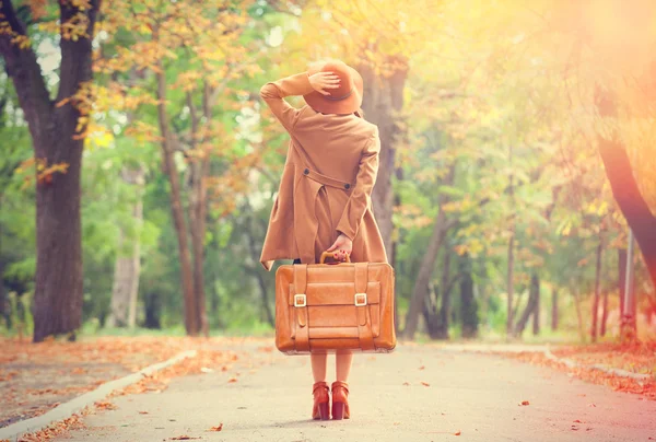 Redhead girl with suitcase in the autumn park. — Stock Photo, Image