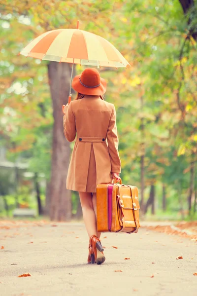 Redhead girl with umbrella and suitcase in the autumn park. — Stock Photo, Image