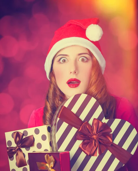 Pelirroja chica con regalos sobre fondo rojo —  Fotos de Stock