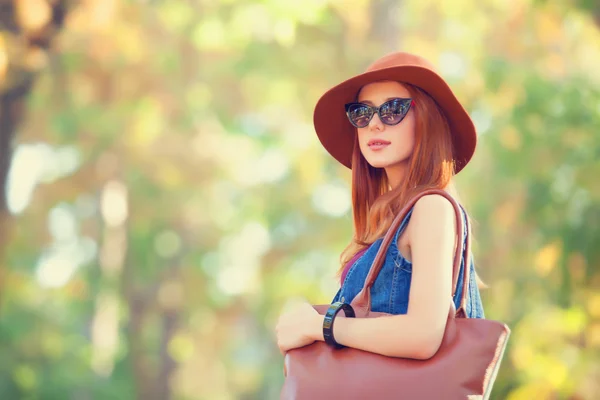 Güzel kızıl saçlı kız parkta bir çanta. — Stok fotoğraf