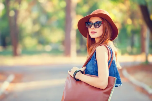 Gyönyörű vörös hajú lány táskáját a parkban. — Stock Fotó