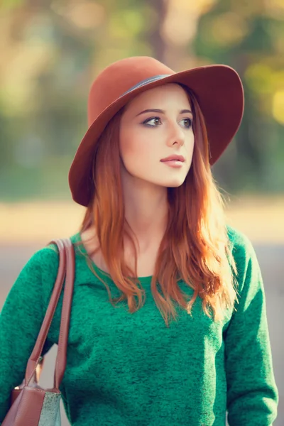 Roodharige meisje in hoed in de herfst park. — Stockfoto