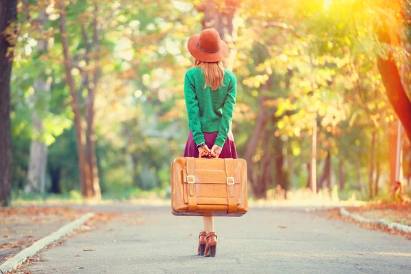 Bella ragazza rossa con valigia nel parco . — Foto Stock