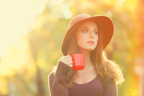 Schöne rothaarige Mädchen mit Tasse im Park. — Stockfoto