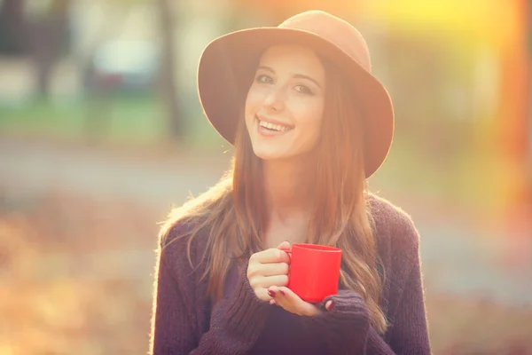 Beautiful redhead girl with cup in the park. — Stock Photo, Image