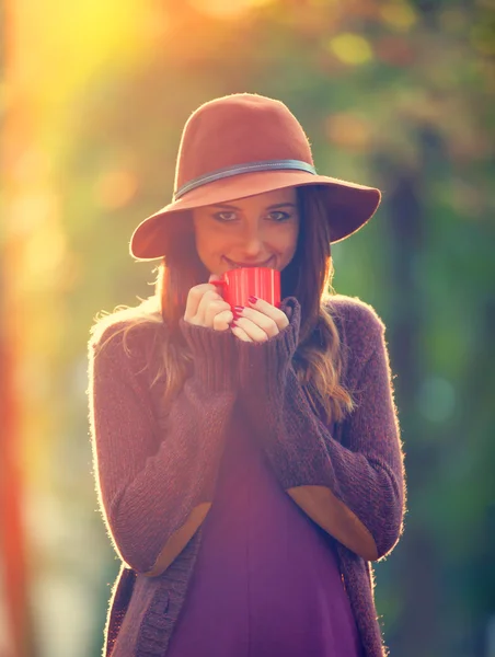 Mooi roodharig meisje met kop in het park. — Stockfoto