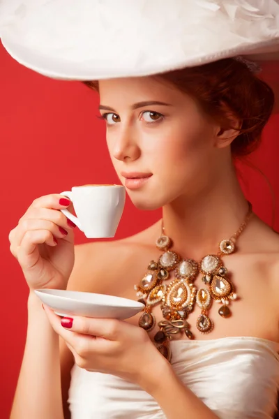 Portret van de roodharige Edwardiaanse vrouw met cup op rode achtergrond. — Stockfoto