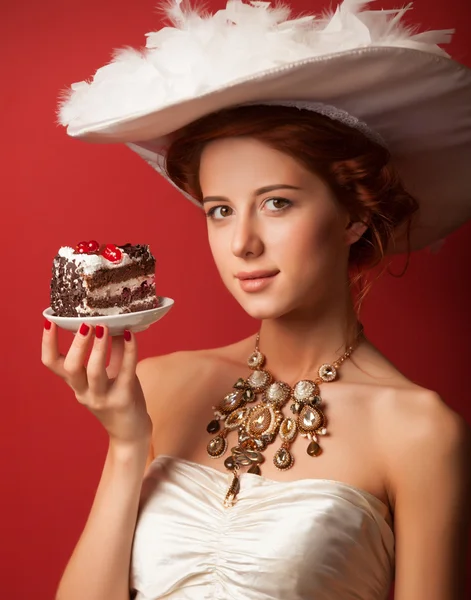 Portret van roodharige Edwardiaanse vrouwen met taart op rode achtergrond. — Stockfoto