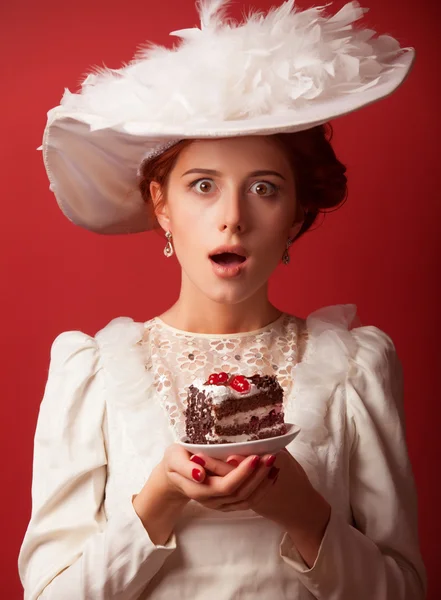 Porträtt av redhead edwardian kvinnor med tårta på röd bakgrund. — Stockfoto