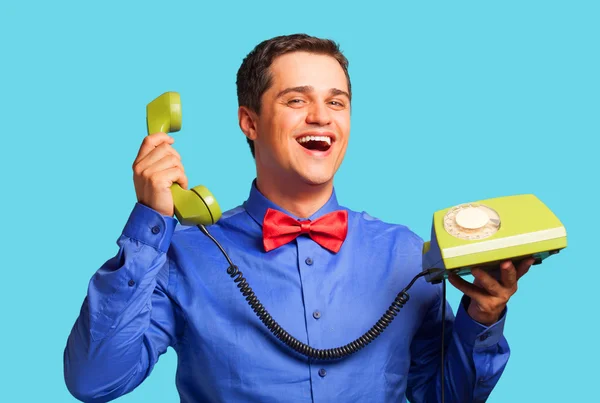 Mavi zemin üzerine yeşil telefon ile mutlu bir adam — Stok fotoğraf