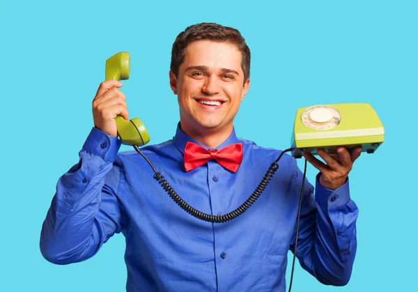 Mavi zemin üzerine yeşil telefon ile mutlu bir adam — Stok fotoğraf
