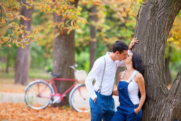 Pareja adolescente con bicicleta retro besándose en el parque en otoño —  Fotos de Stock