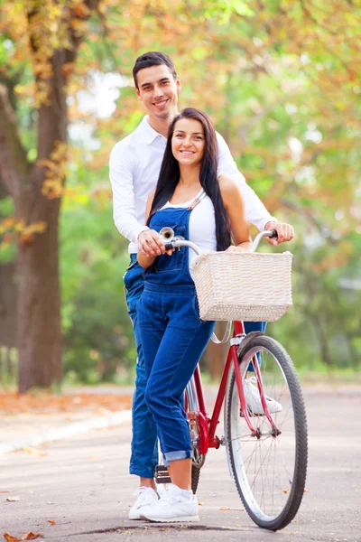 Casal de adolescentes com bicicleta no parque no outono — Fotografia de Stock