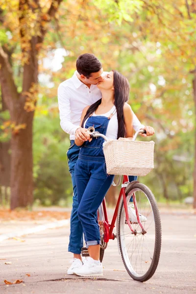 Teen par med retro cykel kyssar i parken i höstens tid — Stockfoto