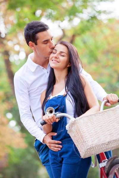 Teen couple with retro bike kissing in the park in autumn time — Stock Photo, Image