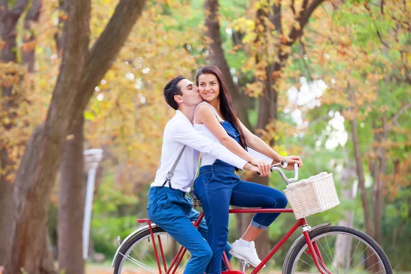 Teen couple with retro bike kissing in the park in autumn time — Stock Photo, Image