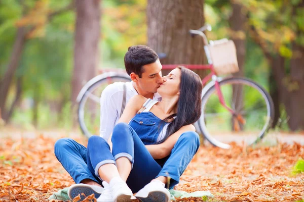 Teen couple with retro bike kissing in the park in autumn time — Stock Photo, Image