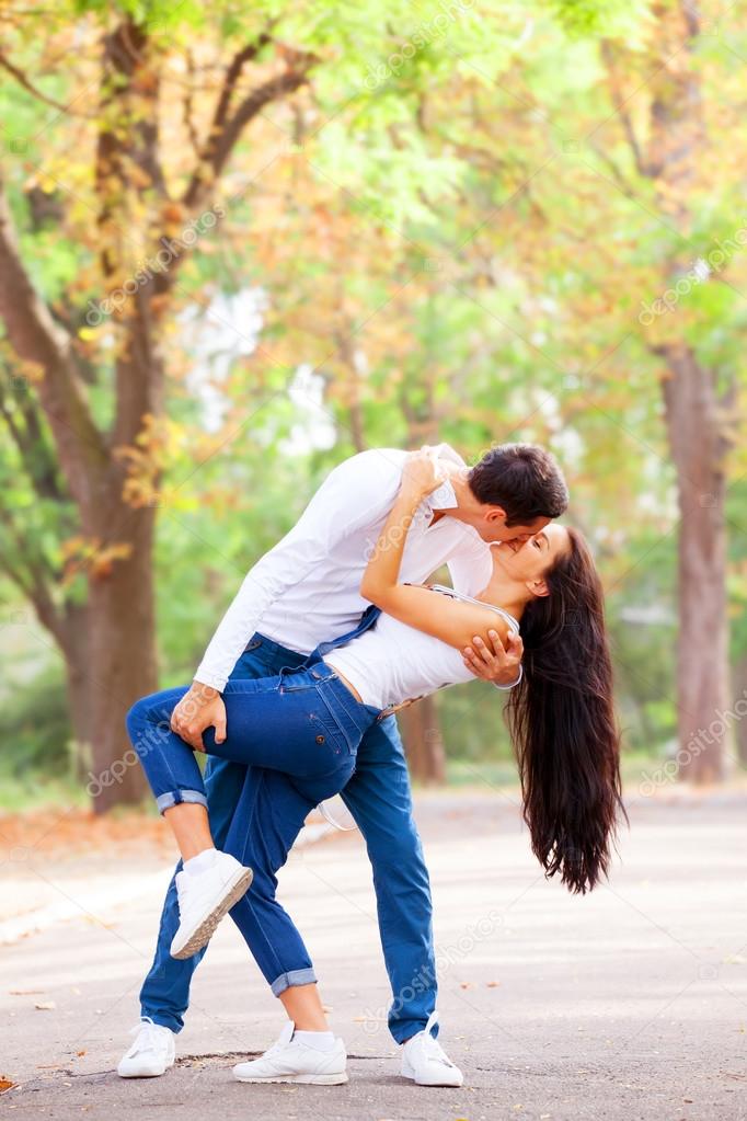 Teen couple kissing in the park in autumn time