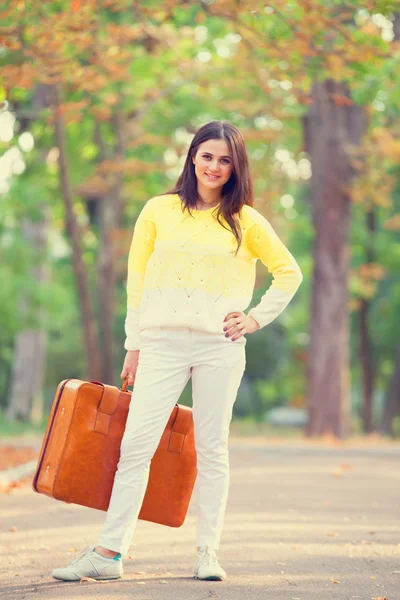 Mooie brunette meisje met koffer in het park. — Stockfoto