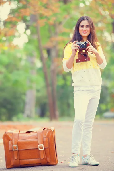 Mooie brunette meisje met koffer in het park. — Stockfoto