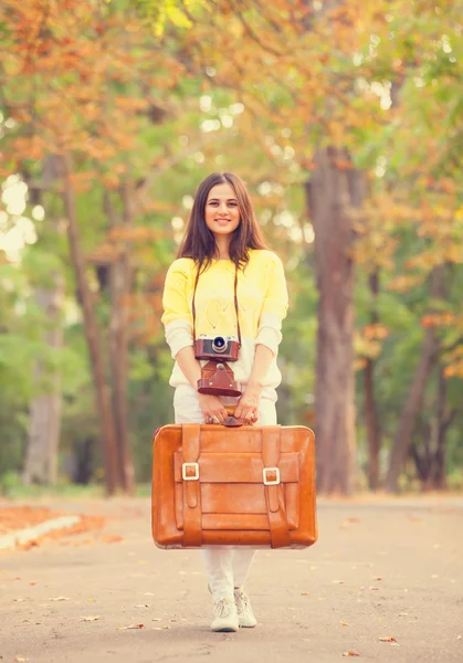 Mooie brunette meisje met koffer in het park. — Stockfoto