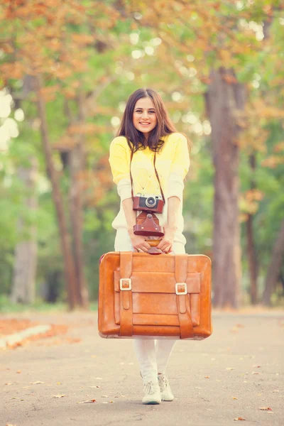 Mooie brunette meisje met koffer in het park. — Stockfoto