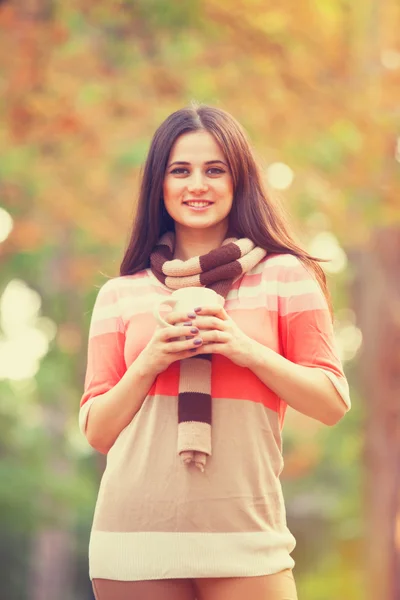 Beautiful brunette girl with cup in the park. — Stock Photo, Image