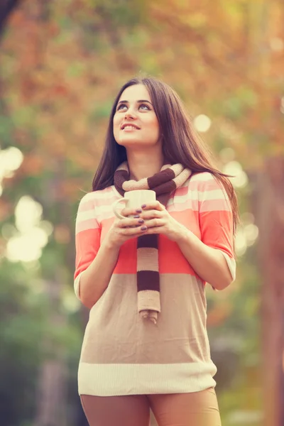 Mooi brunette meisje met kopje in het park. — Stockfoto