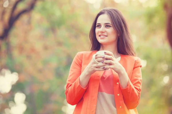 Bella ragazza bruna con tazza nel parco. — Foto Stock