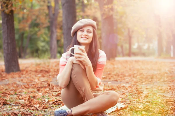 Mooi brunette meisje met kopje in het park. — Stockfoto