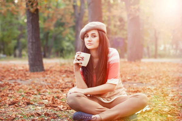 Bella ragazza bruna con tazza nel parco. — Foto Stock