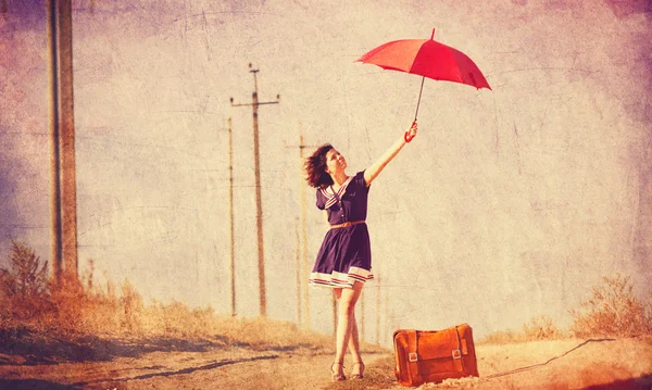 Schöne brünette Mädchen mit Koffer und Regenschirm auf dem Countr — Stockfoto