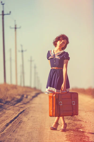 Mooie brunette meisje met koffer op het veld — Stockfoto