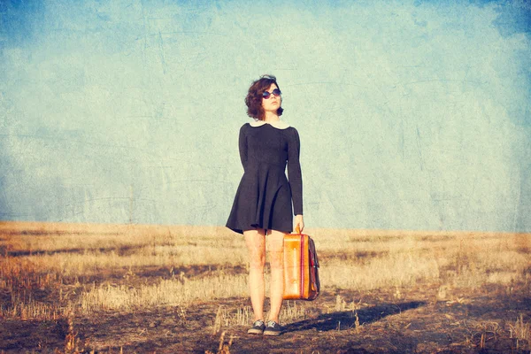 Mooie brunette meisje met koffer op het veld — Stockfoto