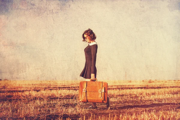 Beautiful brunette girl with suitcase on the field — Stock Photo, Image