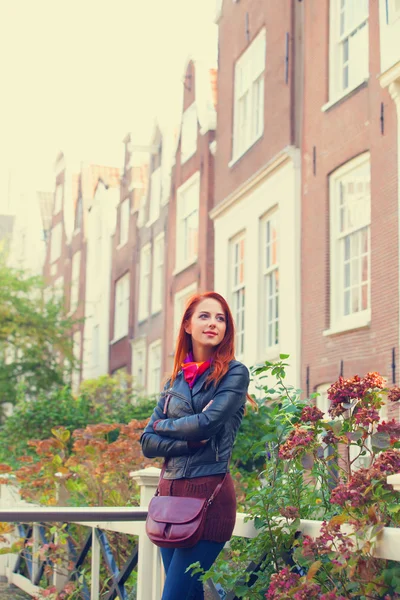 Όμορφη κοκκινομάλλα κοπέλα κοντά σε σπίτια στο Άμστερνταμ. — Φωτογραφία Αρχείου