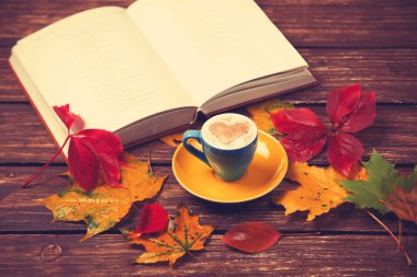 Sonbaharda yapraklar, ahşap masa kitap ve kahve Kupası.