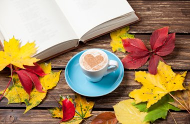 Sonbaharda yapraklar, ahşap masa kitap ve kahve Kupası.