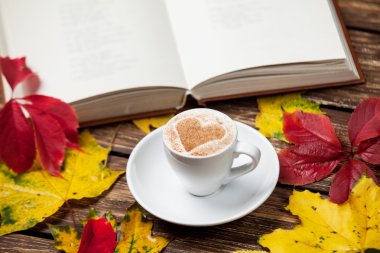 Sonbaharda yapraklar, ahşap masa kitap ve kahve Kupası.