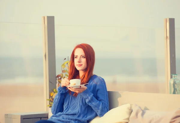 Ragazza rossa con tazza seduta nel caffè vicino alla costa del mare . — Foto Stock